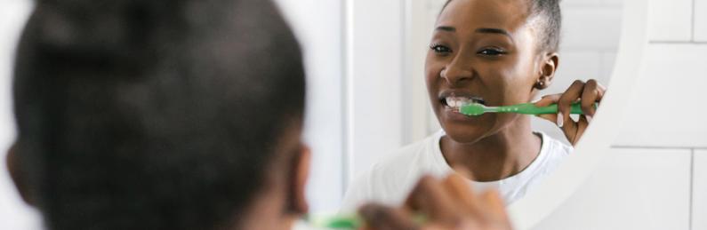 girl brushing teeth in mirror 1600x522